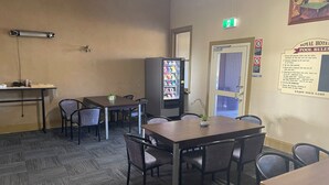 A room with a pool table, chairs, a vending machine, and a door with an exit sign. - Royal Hotel (Yeoval)