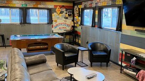A cozy lounge area with a pool table, leather sofa, and a television.