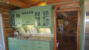 A kitchen with green cabinets, a granite countertop, and a stainless steel refrigerator. - Pine Grove Estate: Beautiful Log home on 40 acres with fantastic Mountain Views (Ridgway)