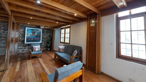 A wooden-floored room with a sofa, a chair, and a painting on the wall. - Bosco Hotel Boutique (Cusco)