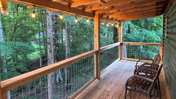 A wooden deck with a railing, overlooking a forested area.