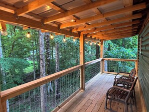 Eine Holzterrasse mit Geländer, mit Blick auf ein bewaldetes Gebiet.