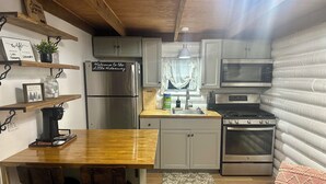 A compact kitchen with a wooden bar, stainless steel appliances, and a cozy seating area.