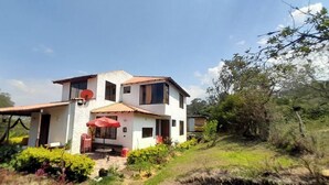 Une maison à deux étages dotée d’un patio et entourée de verdure.