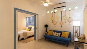 A modern living room with a blue sofa, a bed with white bedding, and a wall decorated with hanging dream catchers.