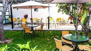 Un espace extérieur aménagé en terrasse, avec des tables et des chaises rondes, des parasols et des plantes en pot.