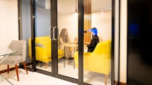 Un intérieur moderne avec une cloison en verre, des sièges jaunes et une table avec des chaises.