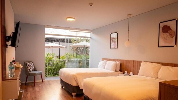 Une chambre d’hôtel avec deux lits, un petit bureau, une chaise et un balcon équipé de parasols.