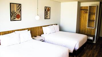 Habitación de hotel con dos camas, cabeceros de madera, una mesita de noche y un armario con espejo.
