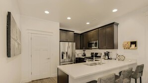 A modern kitchen with dark cabinets, stainless steel appliances, a white countertop, and bar stools. - Outdoor Entertainment, Hot Tub, Modern, Quiet (Flagstaff)