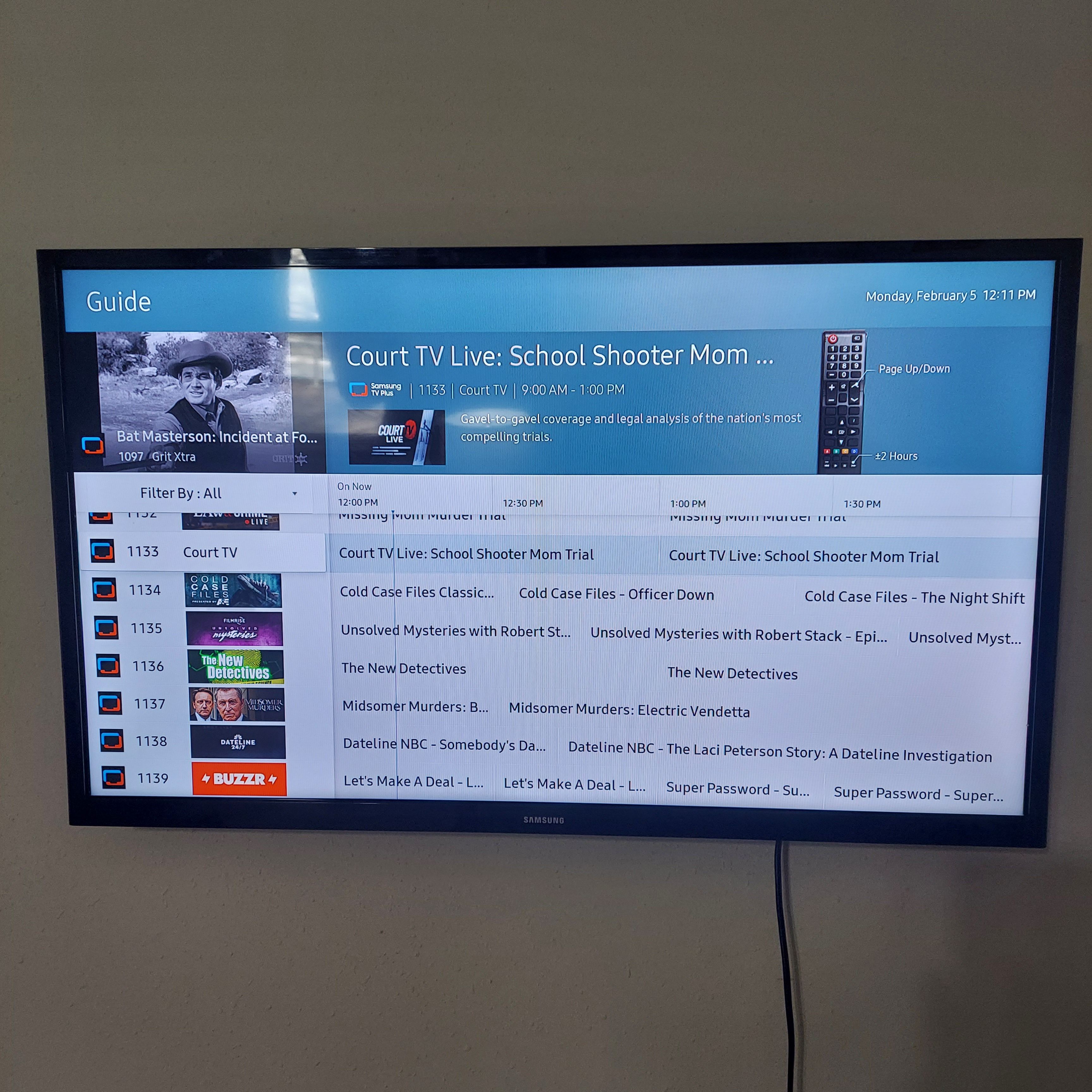 A television screen displaying a guide menu with various TV channels and programs.