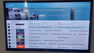 A television screen displaying a guide menu with various TV channels and programs.