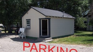 A small building labeled "PARKING" with a gravel driveway and a door leading inside. - Cozy Campground Cabin Cottage with WiFi and AC in charming Greybull (Greybull)