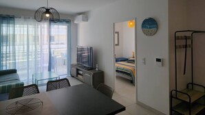 Ett modernt hotellrum med en matplats, en TV, en säng och en balkong med gardiner.