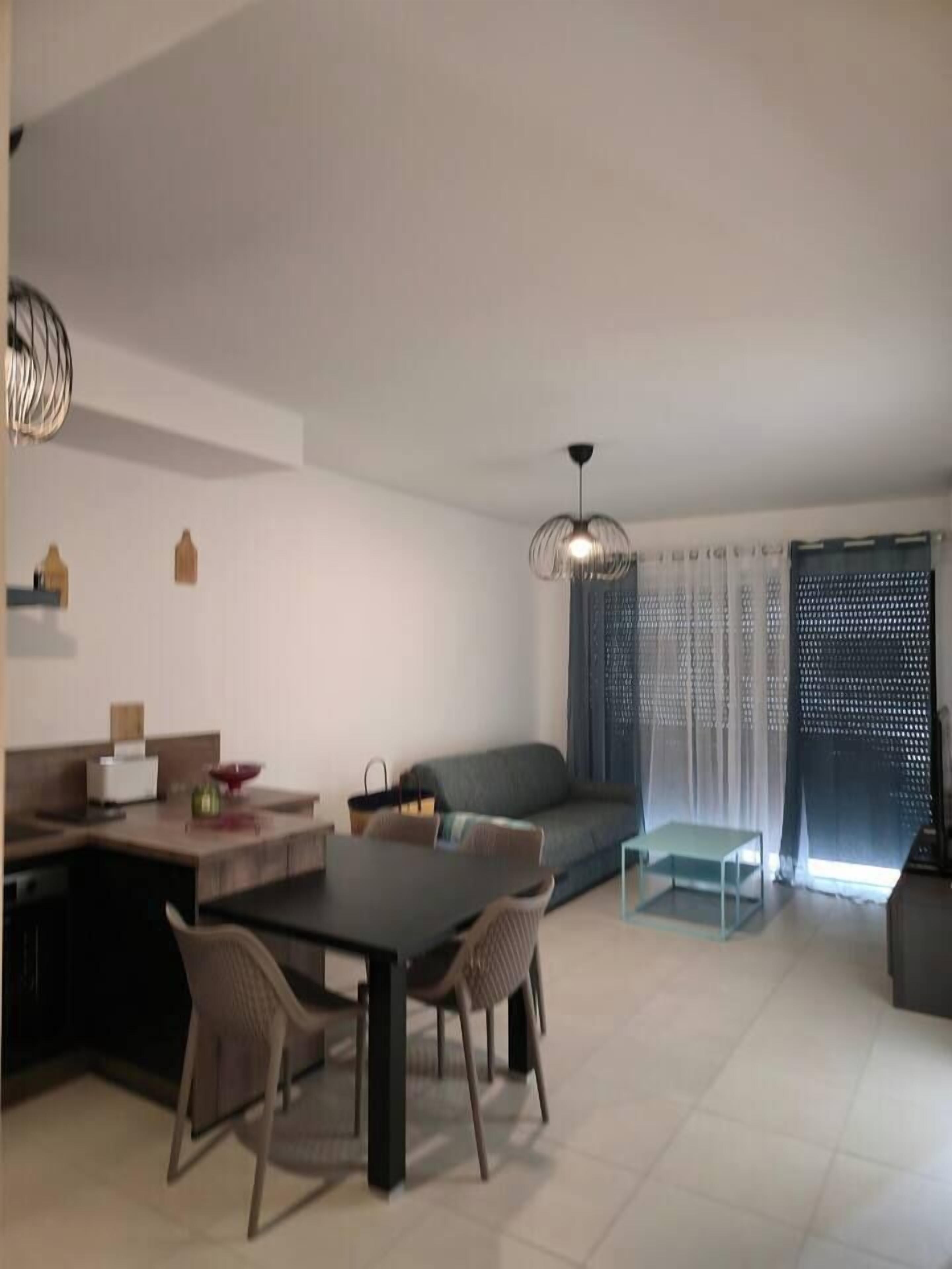 A modern living room with a dining area, a sofa, and a ceiling light fixture.