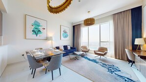 Camera d'albergo moderna con angolo ristoro, divano, scrivania e ampie finestre con vista sulla città.