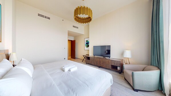 A hotel room with two beds, a TV, a desk, and a chair.