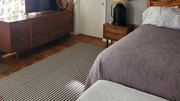 A bedroom with a bed, a dresser, a nightstand, a lamp, and a picture on the wall. - Charming 1-bedroom apt Buffalo WY, on creek, AC,  WiFi, & 1 block from downtown. (Buffalo)