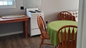 A compact kitchen with a white stove, wooden chairs, and a green tablecloth. - Charming 1-bedroom apt Buffalo WY, on creek, AC,  WiFi, & 1 block from downtown. (Buffalo)