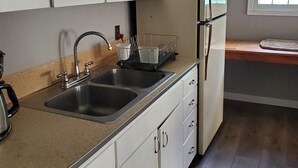 A kitchen with two sinks, a refrigerator, and cabinets. - Charming 1-bedroom apt Buffalo WY, on creek, AC,  WiFi, & 1 block from downtown. (Buffalo)