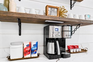 Una cocina con cafetera, azúcar y leche en la encimera.