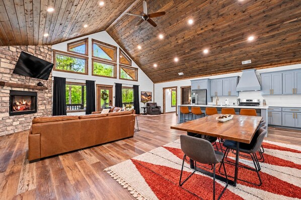A spacious living area with a fireplace, a large sofa, and a dining table with chairs.