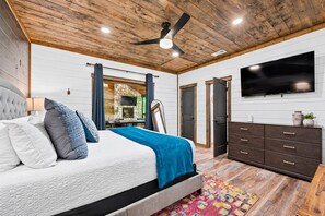 A bedroom with a bed, a dresser, a television, and a ceiling fan. - Creekside Cabin | Hot Tub | Games & Fire Pit (Broken Bow)