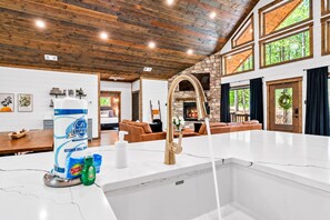 A kitchen with a marble countertop, a gold faucet, and kitchen essentials. - Creekside Cabin | Hot Tub | Games & Fire Pit (Broken Bow)