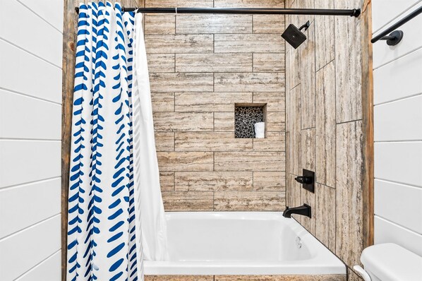 A bathroom with a bathtub, wooden wall paneling, a shower curtain, and a towel rack.