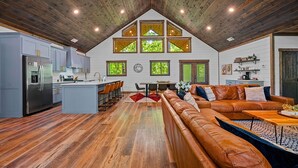 A spacious kitchen with modern appliances, a dining area with a red rug, and a cozy living room with a leather sofa.