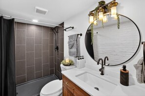A modern bathroom with a shower, toilet, sink, and a large mirror. - Near UPMC, CMU, Pitt & Walnut + Free Parking (Pittsburgh)