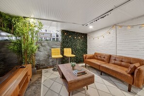 A modern living room with a sofa, two yellow chairs, a coffee table, and a green wall with plants. - Near UPMC, CMU, Pitt & Walnut + Free Parking (Pittsburgh)