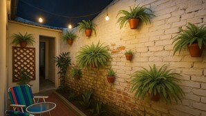 Una terrazza con un muro in mattoni, piante in vaso e mobili da esterno.