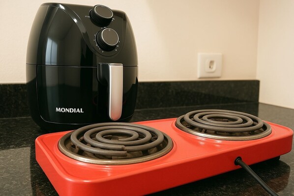 A black Mondial electric kettle and a red electric stove with two burners on a kitchen counter. - Kambô Guest House (Sao Paulo)