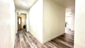 Un couloir avec un plancher en bois et des murs blancs.