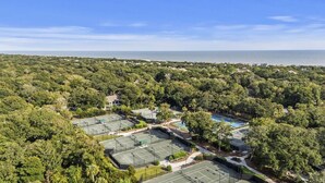 Zona residencial con múltiples canchas de tenis, una piscina y abundante vegetación.