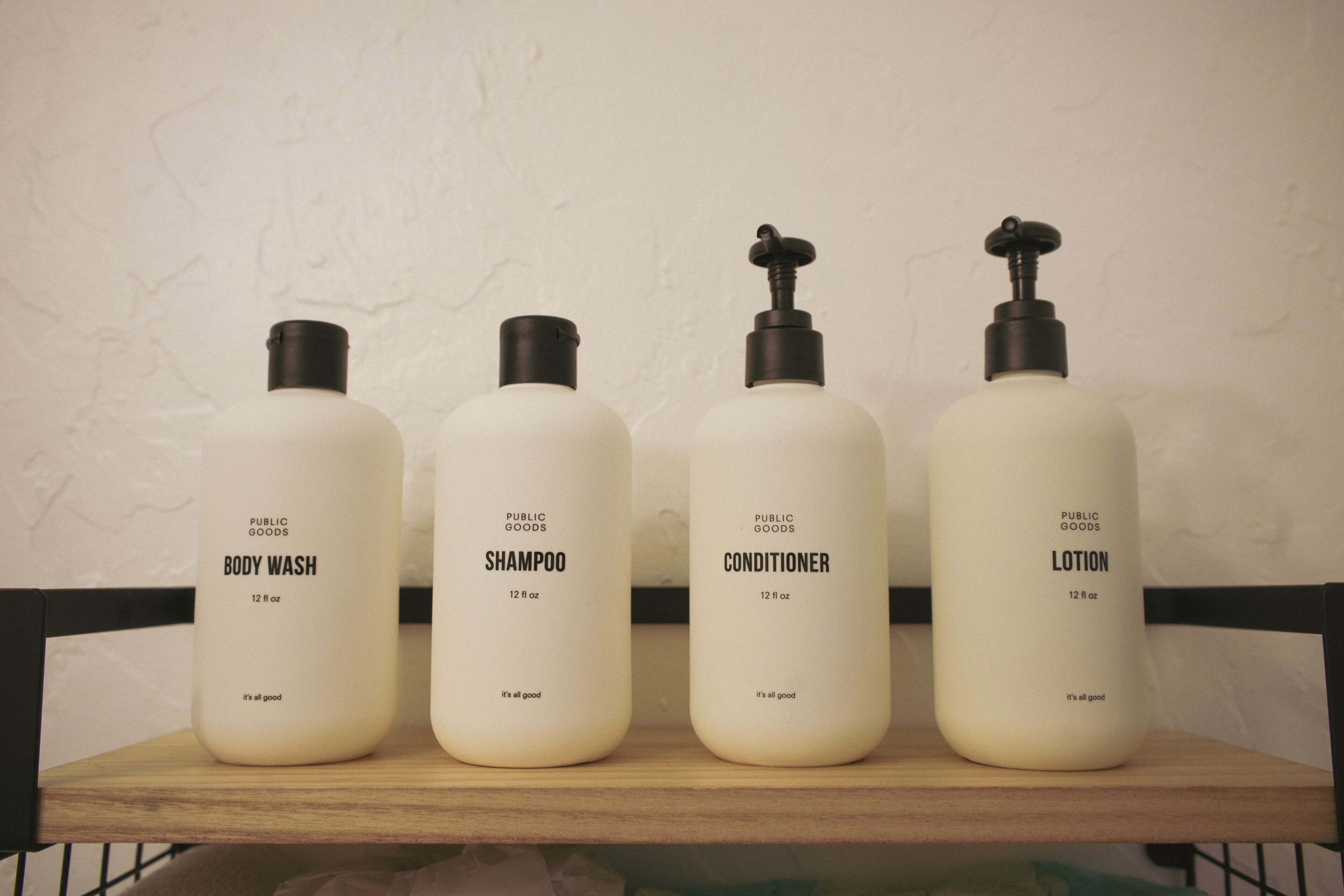 Four bottles of personal care products on a wooden shelf.