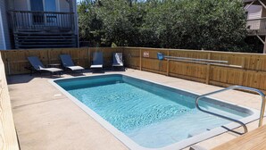Una piscina rettangolare circondata da un solarium in legno, dotata di lettini e scaletta.