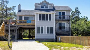 A two-story house with a balcony, a covered porch, and a wooden deck. - Joint Venture: Private Pool, Short Walk to Beach and Currituck Lighthouse (Corolla)