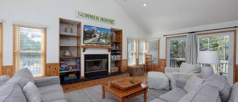 A cozy living room with a fireplace, a bookshelf, and a ceiling fan.
