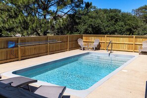 A rectangular swimming pool with a wooden deck, two Adirondack chairs, and a wooden fence. - Joint Venture: Private Pool, Short Walk to Beach and Currituck Lighthouse (Corolla)