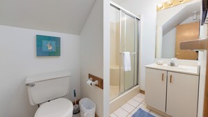 Un bagno con un water, una doccia, un lavandino e uno specchio.