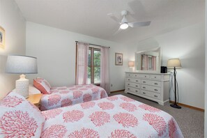 A bedroom with two beds, a ceiling fan, a dresser, and a nightstand with lamps. - Joint Venture: Private Pool, Short Walk to Beach and Currituck Lighthouse (Corolla)