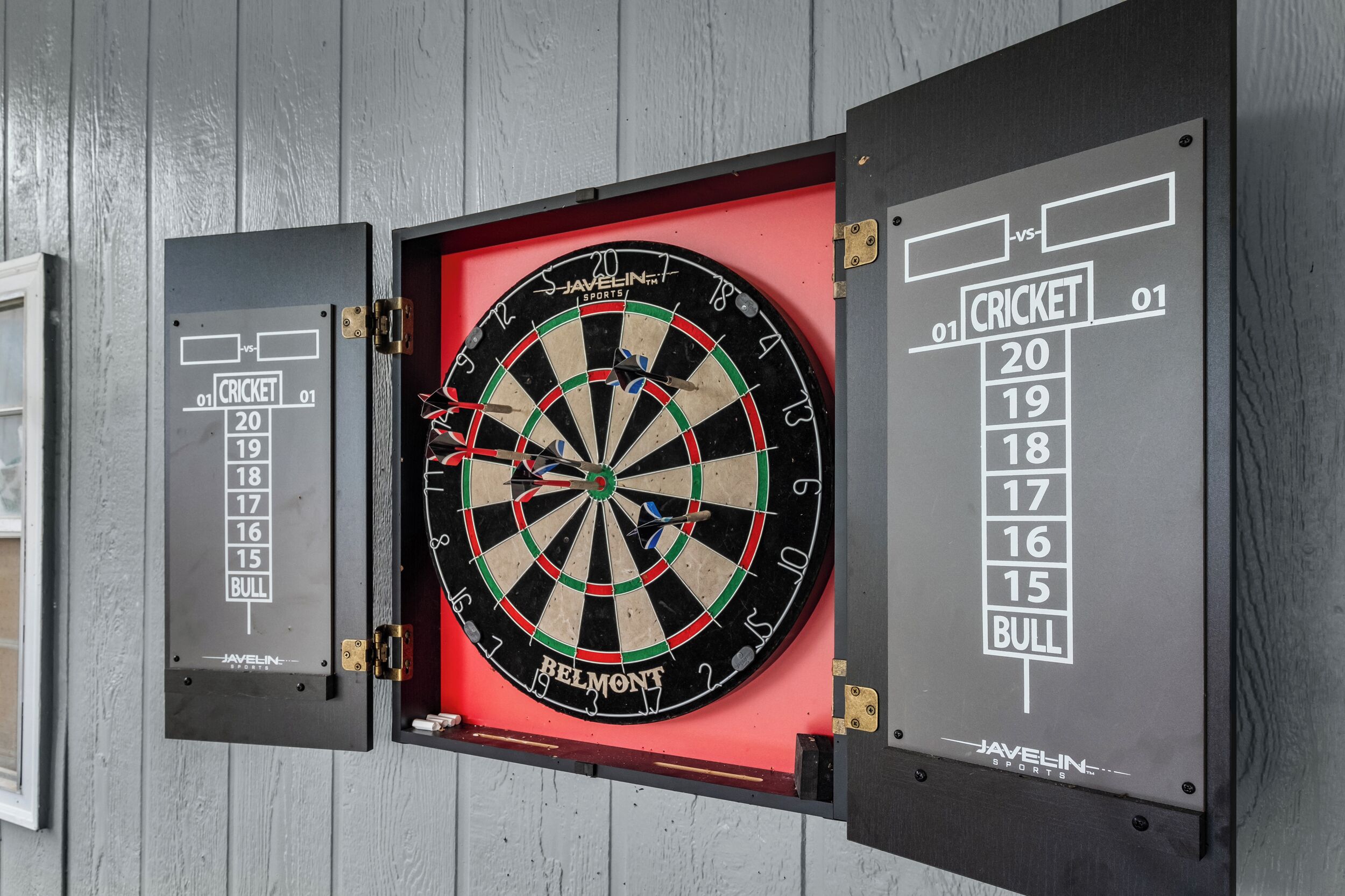 Un jeu de fléchettes fixé au mur, avec un tableau de pointage et un support pour les fléchettes.