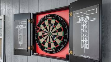 Un jeu de fléchettes fixé au mur, avec un tableau de pointage et un support pour les fléchettes.