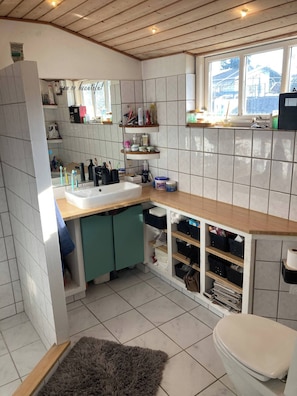 A modern kitchen with a wooden countertop, white tiles, and built-in storage.