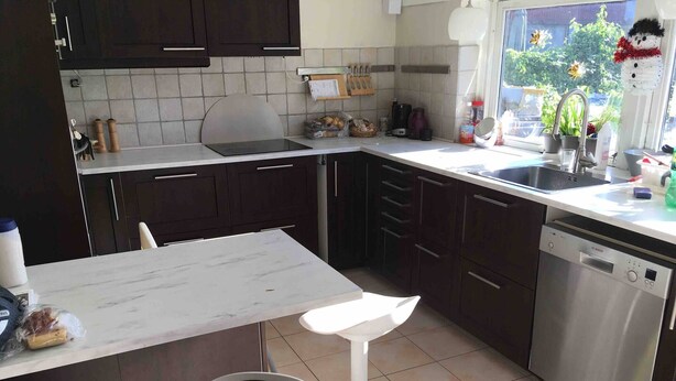 A modern kitchen with dark cabinets, a white countertop, a Bosch dishwasher, and a window with a view of greenery. - Big House in Beautiful Area (Rødovre)