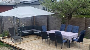 A wooden deck with a built-in seating area, including a sofa and a table with chairs. - Big House in Beautiful Area (Rødovre)
