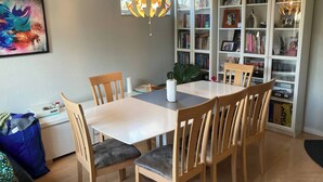 A dining area with a white table, wooden chairs, and a hanging light fixture. - Big House in Beautiful Area (Rødovre)
