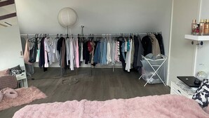A bedroom with a bed, a closet with clothes, a floor lamp, and a desk with a laptop. - Big House in Beautiful Area (Rødovre)